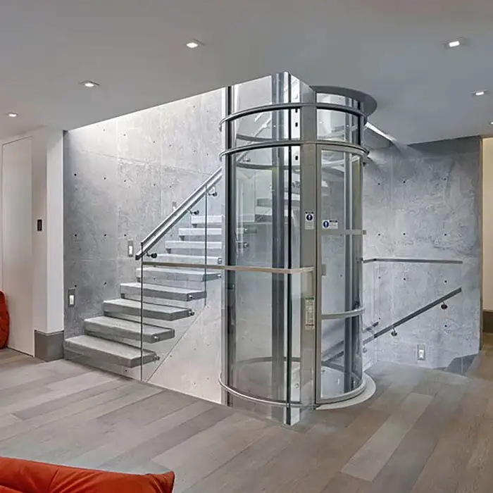 A round home lift installed in a stairwell, surrounded by a glass and steel balustrade